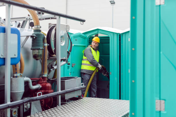 Worker pumping feces out of rental toilet for disposal and cleaning